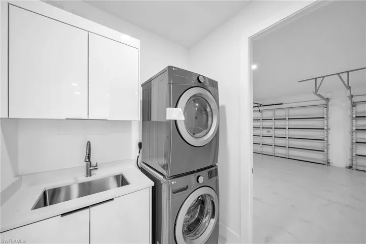 Washroom with cabinets, stacked washer and clothes dryer, and sink