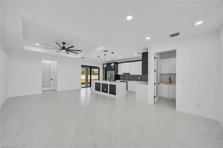 Unfurnished living room featuring a tray ceiling, ceiling fan, and sink
