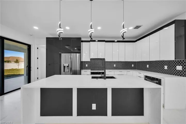Kitchen with sink, white cabinets, pendant lighting, and stainless steel refrigerator with ice dispenser