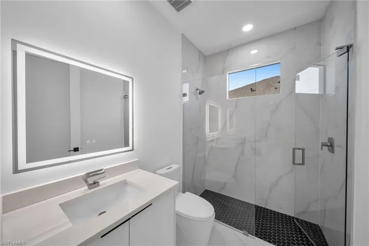 Bathroom with vanity, toilet, and a shower with shower door