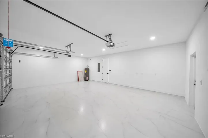 Garage with electric panel, electric water heater, and a garage door opener