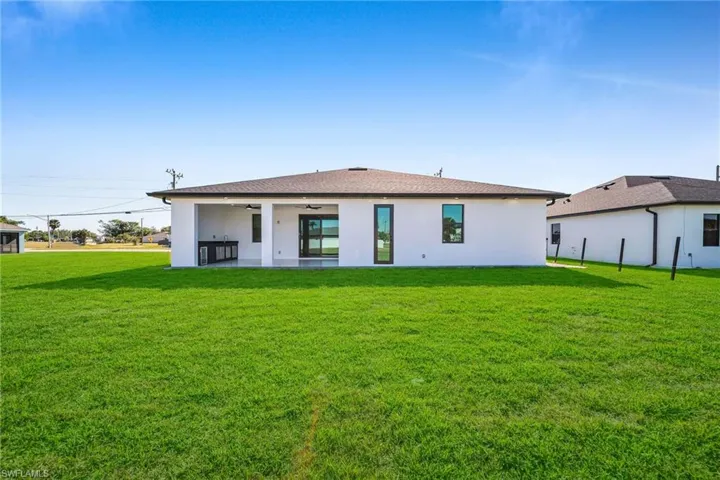 Rear view of property with a patio, ceiling fan, and a lawn