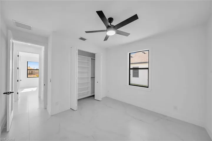 Unfurnished bedroom with ceiling fan and a closet