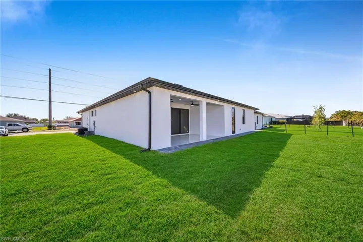 View of side of property with ceiling fan and a yard