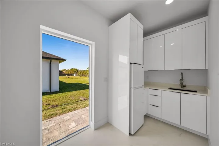 Kitchen with white cabinets, white fridge, and sink