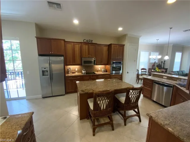 Kitchen featuring plenty of natural light, appliances with stainless steel finishes, a breakfast bar, light stone countertops, and recessed lighting