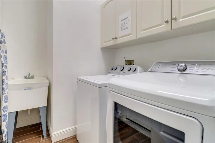 Washroom with hardwood / wood-style flooring, cabinets, and separate washer and dryer