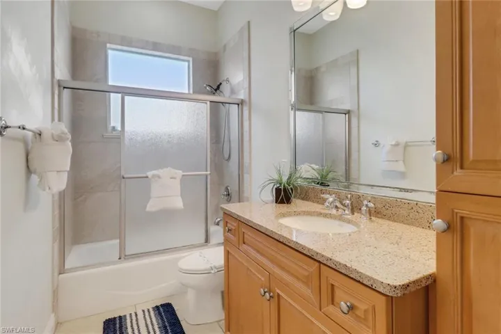 Full bathroom with tile patterned flooring, vanity, toilet, and enclosed tub / shower combo
