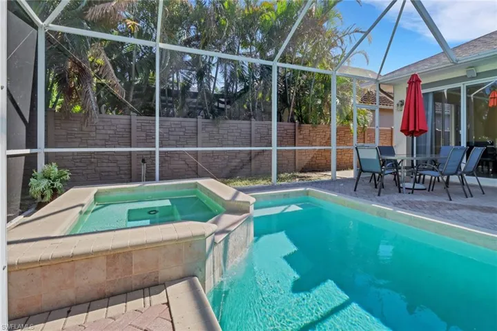 View of swimming pool with glass enclosure, an in ground hot tub, and a patio