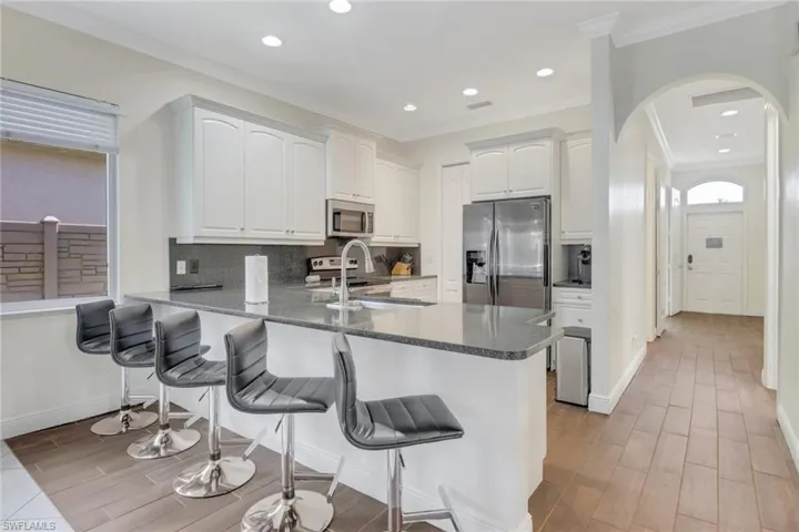 Kitchen with kitchen peninsula, sink, white cabinets, and appliances with stainless steel finishes
