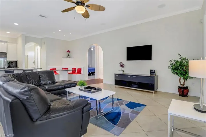Tiled living room featuring ceiling fan and crown molding