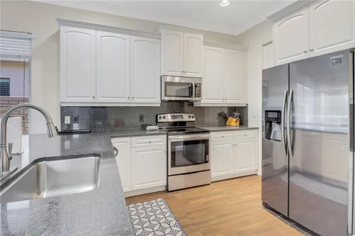 Kitchen featuring white cabinets, appliances with stainless steel finishes, backsplash, and sink
