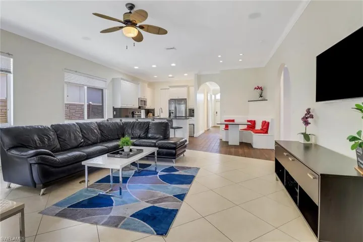 Living room featuring ceiling fan, sink, light wood-type flooring, and ornamental molding