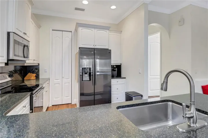 Kitchen with sink, stainless steel appliances, crown molding, white cabinets, and hardwood / wood-style flooring