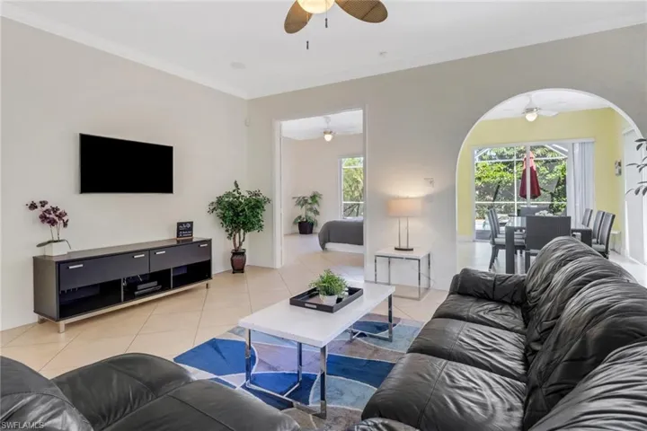 Tiled living room with a wealth of natural light, crown molding, and ceiling fan