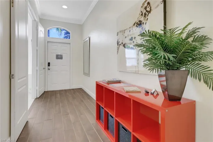 Foyer entrance with wood-type flooring and ornamental molding