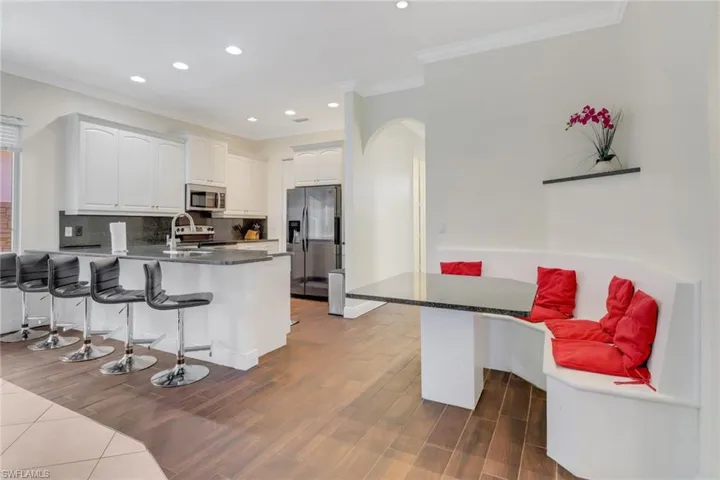Kitchen featuring a kitchen bar, white cabinets, dark hardwood / wood-style flooring, kitchen peninsula, and stainless steel appliances