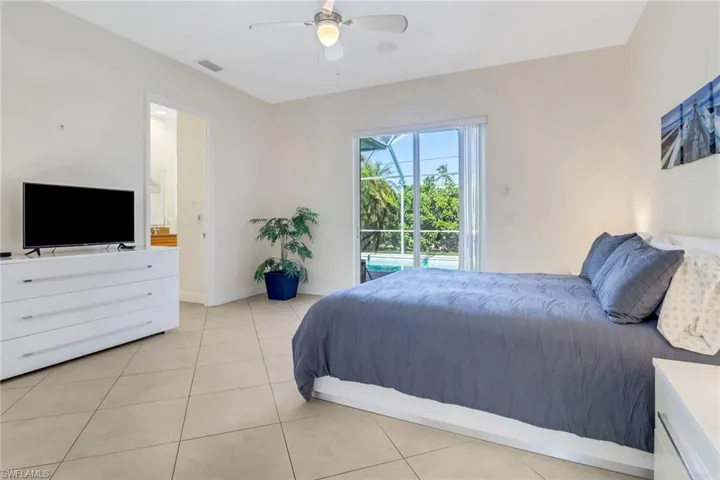 Tiled bedroom featuring ensuite bath and ceiling fan