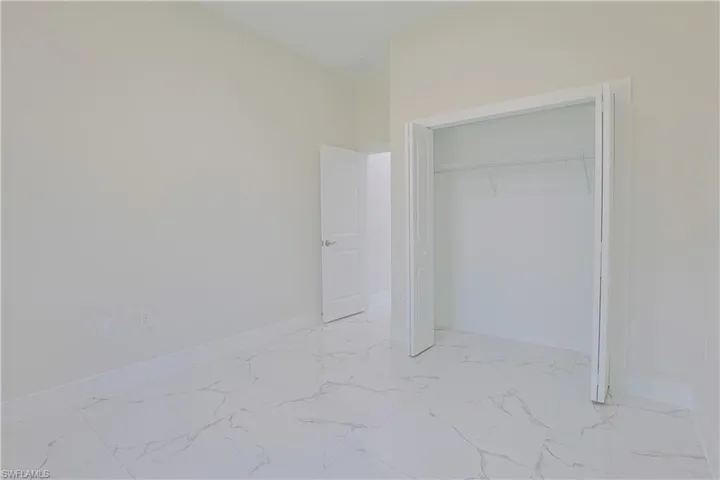 Unfurnished bedroom featuring a closet and light marble finish flooring