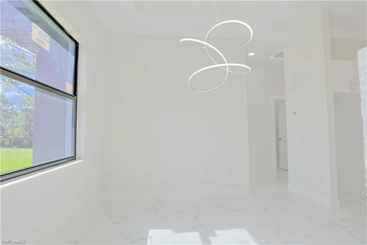 Empty room featuring a chandelier, light marble finish flooring, and recessed lighting