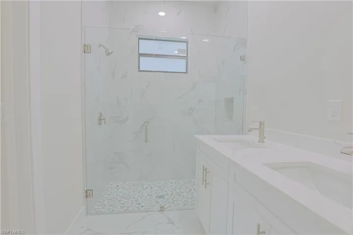 Full bathroom with marble finish flooring, a marble finish shower, and double vanity