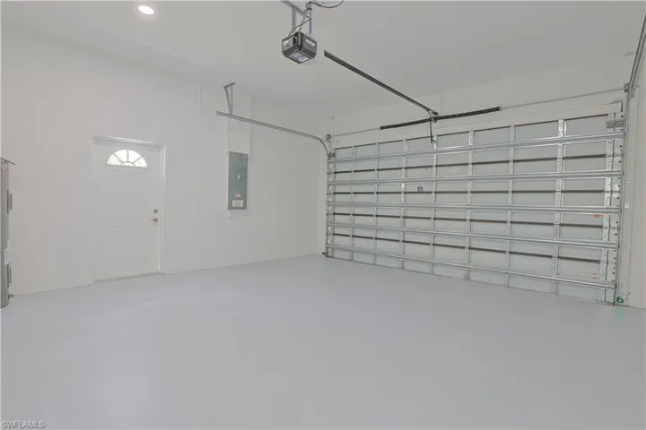 Garage featuring a garage door opener, electric panel, and recessed lighting