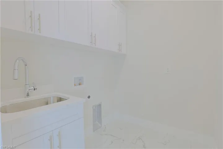 Laundry room featuring hookup for a washing machine, electric dryer hookup, marble finish flooring, and cabinet space