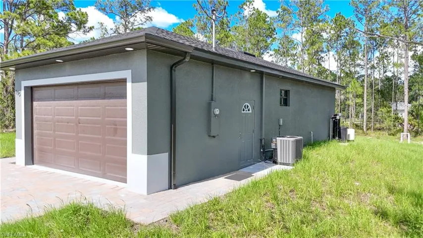 View of home's exterior featuring stucco siding, a garage, driveway, and roof with shingles