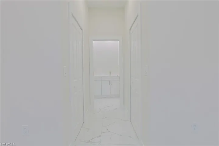 Hallway with light marble finish flooring and baseboards