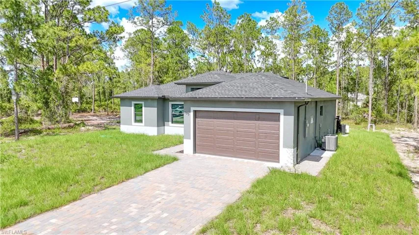 Prairie-style home featuring stucco siding, roof with shingles, an attached garage, and a front yard