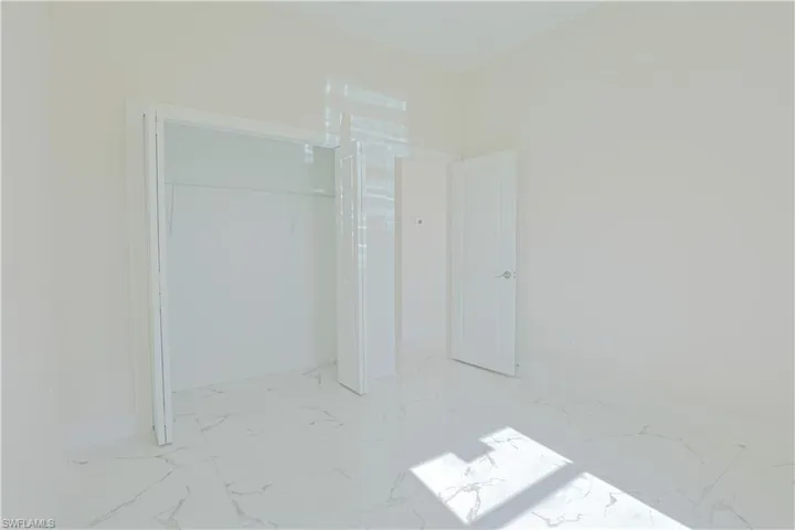 Unfurnished bedroom featuring light marble finish floors and a closet