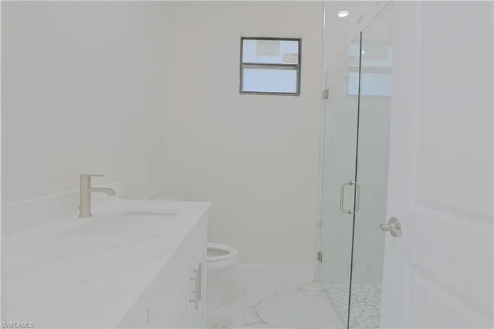 Full bath featuring vanity, marble finish flooring, and a marble finish shower