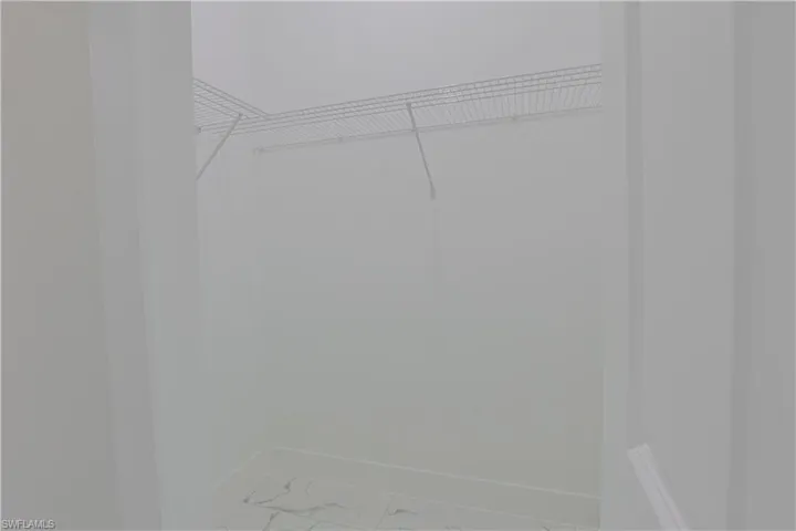 Walk in closet featuring marble finish floors