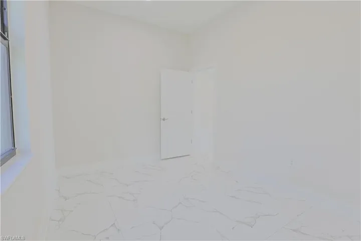 Spare room with marble look tile flooring and baseboards