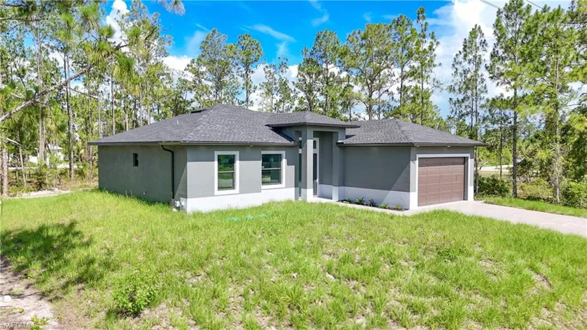 Prairie-style home featuring an attached garage, stucco siding, driveway, and a front lawn