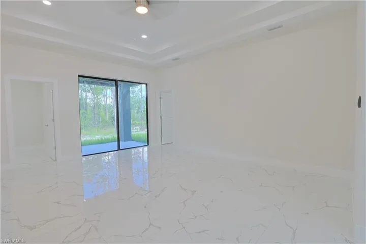 Spare room featuring a tray ceiling, a ceiling fan, light marble finish floors, and recessed lighting