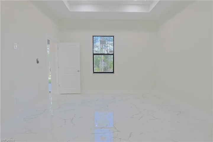 Empty room with a raised ceiling and marble finish floors