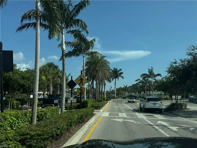 View of asphalt street featuring traffic signs, curbs, and street lighting
