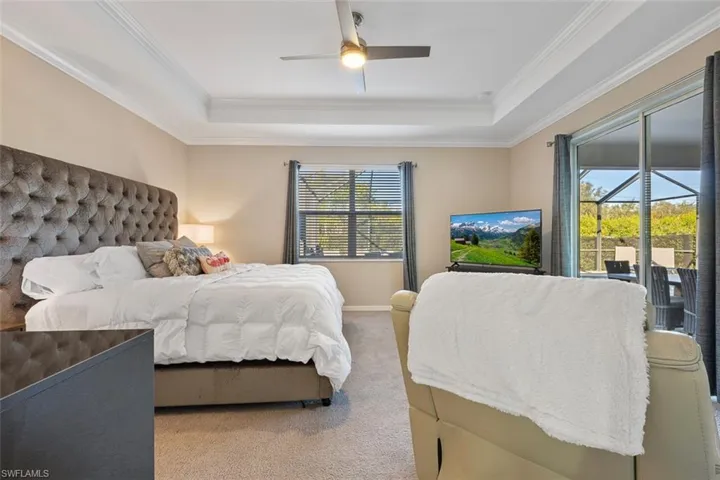 Carpeted bedroom featuring access to outside, ceiling fan, ornamental molding, and a raised ceiling