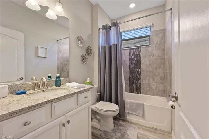 Full bathroom with toilet, vanity, shower / tub combo with curtain, and hardwood / wood-style flooring