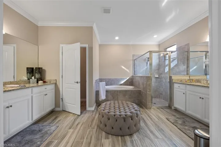 Bathroom featuring vanity, crown molding, and plus walk in shower