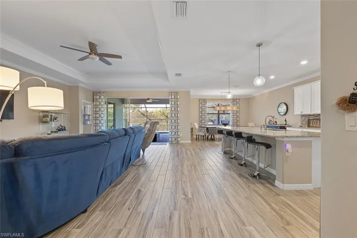 Living room featuring ceiling fan, crown molding, a tray ceiling, and light hardwood / wood-style floors
