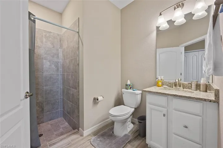 Bathroom featuring tiled shower, vanity, and toilet