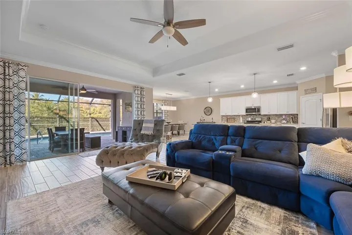 Living room featuring ceiling fan, crown molding, and a tray ceiling