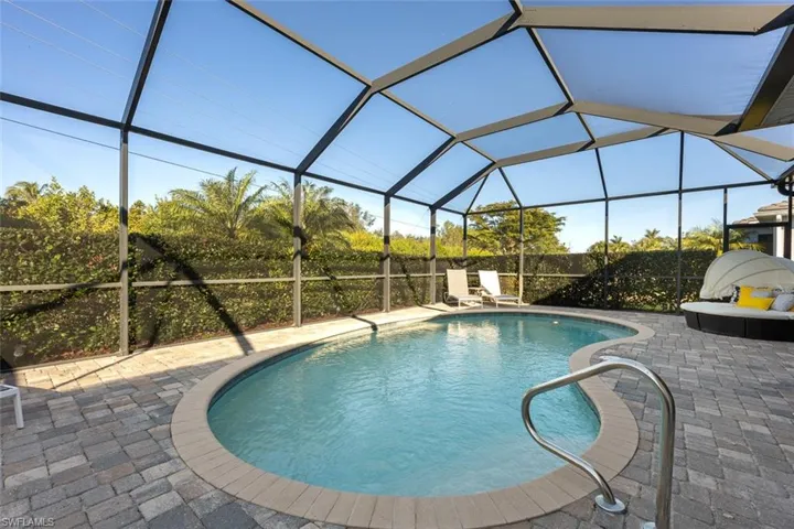 View of pool featuring a patio area and glass enclosure