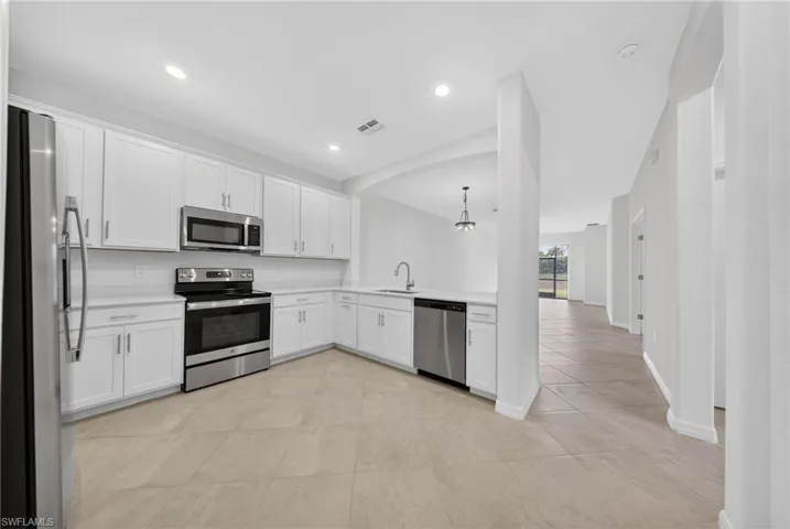 Kitchen with white cabinetry, stainless steel appliances, light countertops, light tile patterned floors, and a peninsula