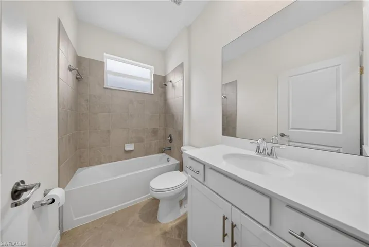 Bathroom with vanity, shower / bathtub combination, and light tile patterned floors