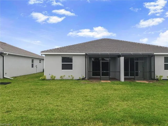 Back of house with a lawn, stucco siding, and a sunroom