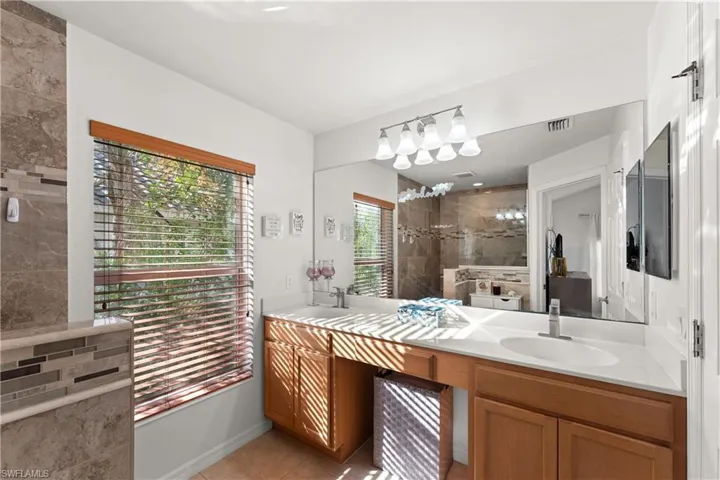 Bathroom featuring vanity, tile patterned floors, and tiled shower
