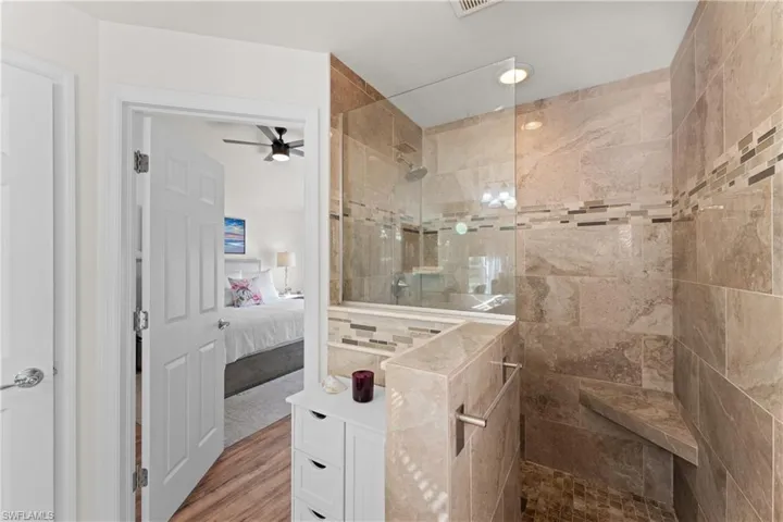 Bathroom with ceiling fan, wood-type flooring, and tiled shower